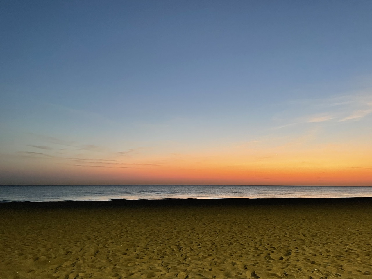 An empty shoreline at dawn, the lake meeting a wide open sky